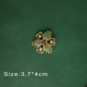 Detailed view of vintage Baroque brooch with green gemstones and white pearls.