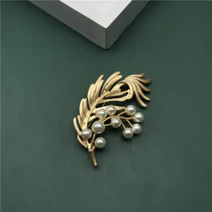 Detail view of vintage gold feather brooch with elegant white pearls for banquet