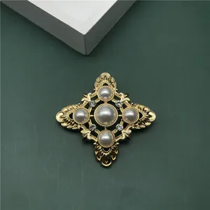 Detail view of gold baroque cross brooch with elegant pearls and sparkling rhinestones