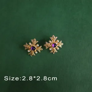 Close-up of vintage Baroque style gold cross brooch with purple gemstone and pearls