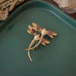 Dettaglio dell'elegante spilla a libellule dorate con smalto e perle