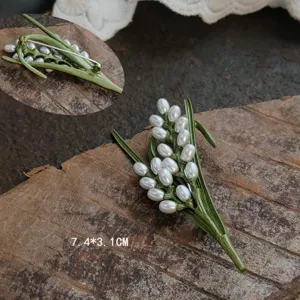 Close-up detail of a vintage lily of the valley brooch featuring enamel leaves and pearls