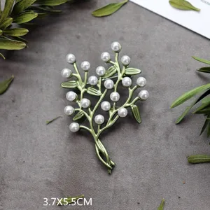 Detailweergave van de vintage bosstijl broche met groene bladeren en witte parels