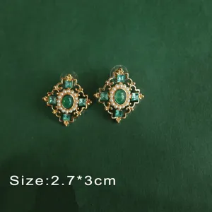Detail of vintage Baroque emerald green gemstone earrings with pearl accents.