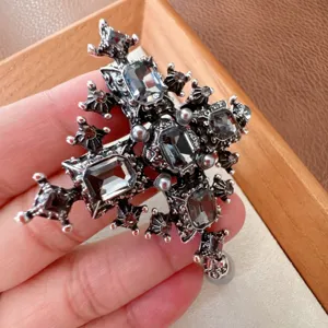 Detail view of a vintage silver-tone cross brooch with black emerald-cut rhinestones