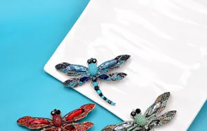 Detail view of colorful rhinestone dragonfly brooches on a white ceramic plate
