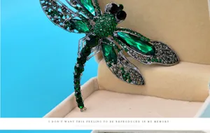 Detailed view of a vintage large dragonfly brooch with sparkling emerald green crystal stones
