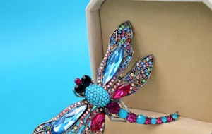 Detailed macro shot of a vintage dragonfly brooch with colorful rhinestones and crystals