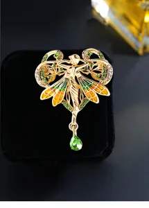 Primer plano de un broche de ángel barroco vintage con cristales verdes y alas esmalte