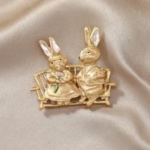 Broche couple de lapins vintage en or mat sur un banc avec des accents d'émail élégants