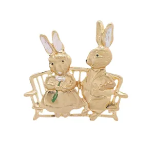 Broche vintage lapins dorés mats assis sur un banc de jardin