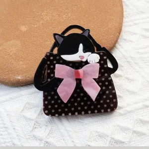 Primer plano de un broche de acrílico con gato en bolsa de lunares y lazo rosa detallado
