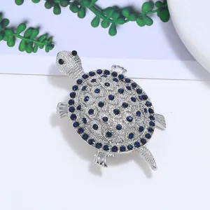 Close-up van een zilverkleurige schildpadspeld met schitterende blauwe kristallen