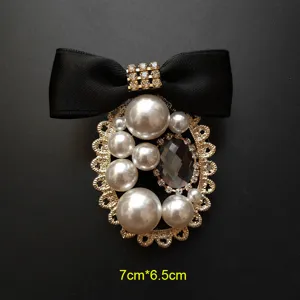 Detalle de un broche de estilo barroco vintage con un lazo negro y perlas blancas