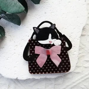 Vista detallada de un broche de acrílico con un gato en una cesta y un lazo rosa
