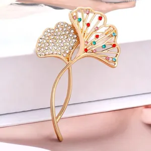 Detailopname van de ginkgobladbroche met veelkleurige strass steentjes en goudkleur