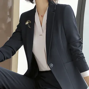 Elegante vintage gouden ginkgoblad broche speld op een marineblauwe blazer dames.