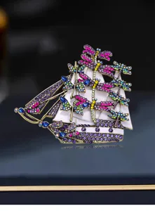 Macro detail view of a vintage sailing ship brooch with colorful rhinestone dragonflies