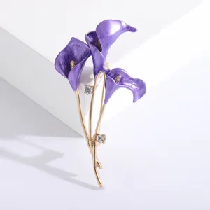 Detail view of a purple enamel calla lily flower brooch with gold finish and crystals