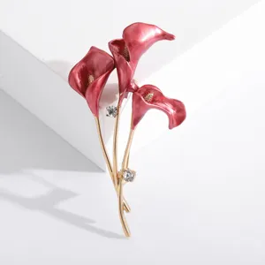 Macro view of elegant red enamel calla lily brooch with gold stems and rhinestones.