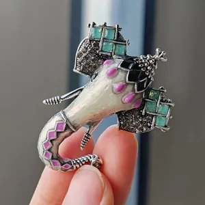 Macro detail view of Thai style elephant brooch with green crystals and purple enamel.