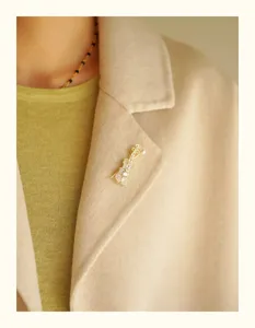 Elegant gold violin brooch with crystals and pearl pinned on a beige wool coat lapel