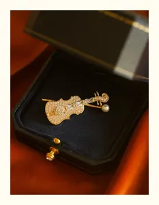 Detailed view of an elegant gold-plated violin brooch with sparkling crystals and pearl
