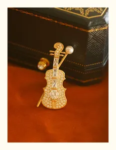 Close-up of an elegant violin brooch with crystal pavé and a white pearl detail.