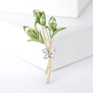 Primer plano de un elegante broche de ramo en esmalte verde con detalle de mariposa de diamantes.