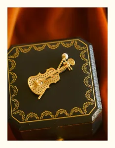 Detail of an elegant golden violin brooch with sparkling zircons and a small pearl.