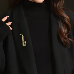 Elegant gold-toned saxophone brooch with rhinestones worn on a black blazer lapel.