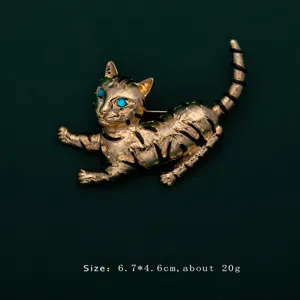 Detail view of a golden cat brooch with blue eyes and black stripes on a green background.
