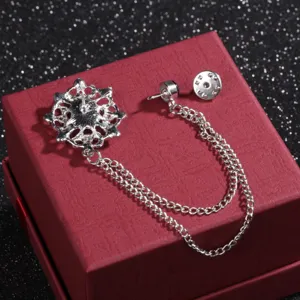 Elegante spilla a doppia catena color argento con fiore in filigrana su una confezione regalo