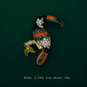 Close-up of a vibrant enamel toucan brooch with sparkling rhinestones on green background