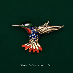 Detail shot of a vibrant colorful enamel hummingbird brooch featuring size and weight specifications