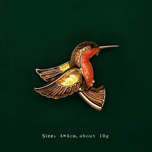 Detailed view of an elegant enameled hummingbird brooch with gold and orange accents.