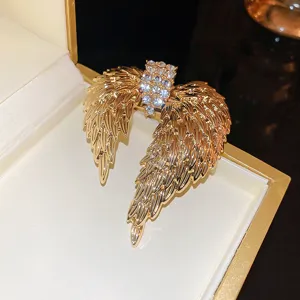 Detailed macro view of a luxury golden rhinestone angel wings brooch inside an elegant gift box