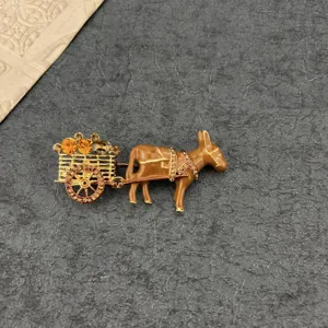 Vintage enamel donkey cart brooch featuring yellow crystal accents on a dark stone surface