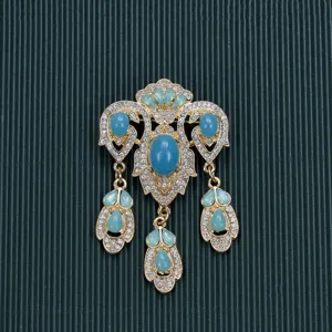 Detailed view of a vintage Baroque style brooch with rhinestones and teal cabochons.