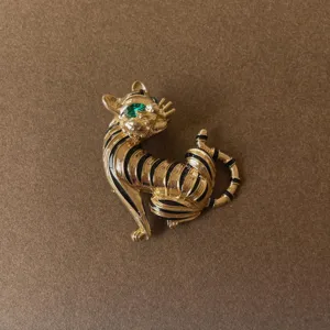 Detailed view of a vintage baroque gold cat brooch with black stripes and green eye