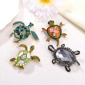 Série de broches tortue vintage avec émail et cristaux sur fond blanc texturé élégant