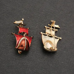 Detailed view showing the front and back of a red enamel sailing ship brooch