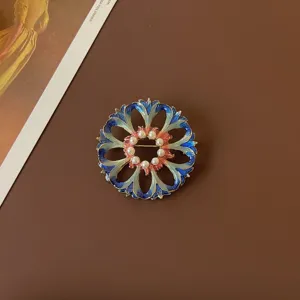 Close-up view of a vintage Baroque enamel floral brooch with delicate white pearls