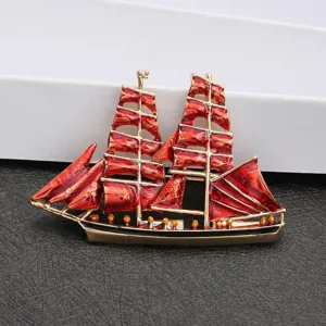 Detailed view of a vintage style red enamel sailboat brooch with gold-toned plating