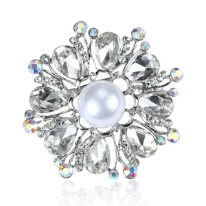 Close-up of elegant floral crystal brooch with white pearl center and silver setting.