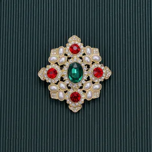 Detailed macro view of a vintage Baroque style brooch with red and green crystals and pearls