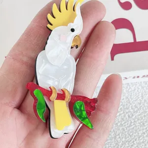 Handheld detail of a colorful acrylic cockatoo brooch with pearlescent finish
