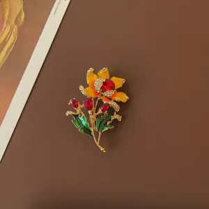 Detailed view of vintage enamel flower brooch with red gems and yellow petals