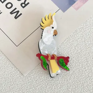 Close-up of a white acrylic cockatoo brooch with yellow crest on a red branch