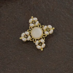 Macro detail of a vintage Baroque style gold cross brooch featuring elegant white pearls